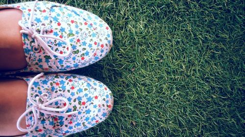 Close-up of kid wearing shoes on grass