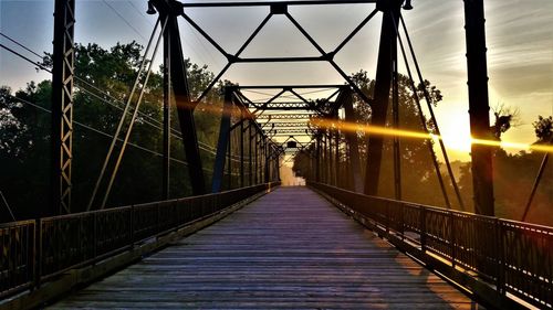 Footbridge against sky at sunset