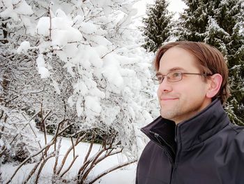 Man looking away against snowy tree during winter