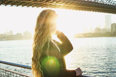 Portrait of woman standing by river in city against sky
