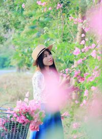 Side view portrait of young woman picking pink flowers at park