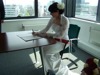 Bride in wedding dress signing document at table