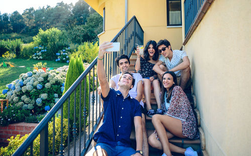 Happy friends taking selfie while sitting on steps