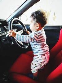 Side view of baby boy playing in car