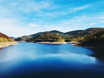 Scenic view of lake by mountains against sky