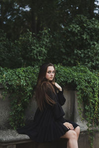 Portrait of woman sitting against trees