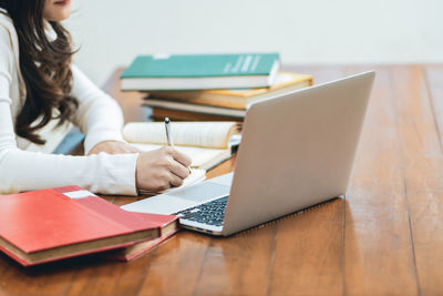 Midsection of woman using mobile phone while sitting on table