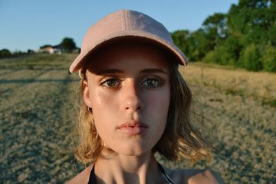 Close-up portrait of beautiful young woman wearing cap on field