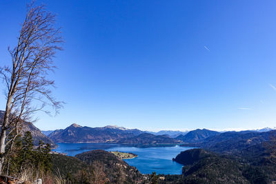 Scenic view of sea and mountains against clear blue sky