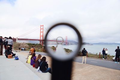 People on bridge against sky in city