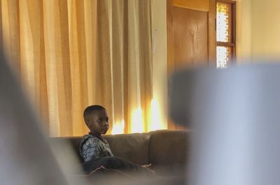 4 year old african boy, on couch, watching tv at home 