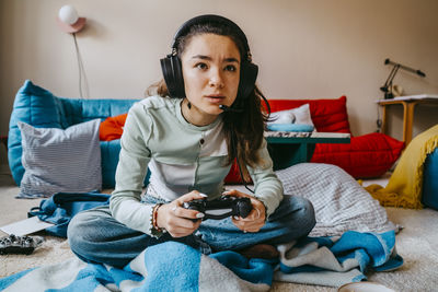 Woman wearing headset playing video game in living room at home