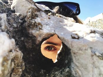 Close-up portrait of woman looking through rock