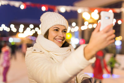 Portrait of smiling young woman in city at night