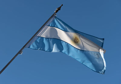 Low angle view of flag against clear blue sky