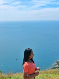 Woman standing by sea against sky