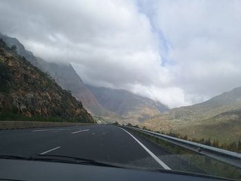 Road amidst mountains seen through car windshield