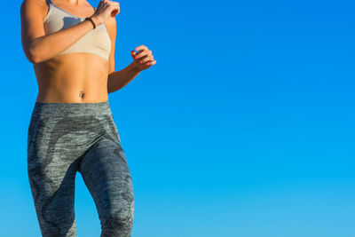 Low angle view of woman standing against clear blue sky