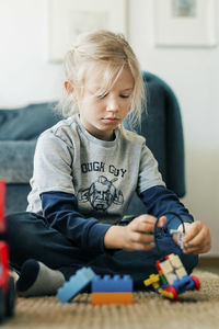 Girl playing block game while sitting on floor at home