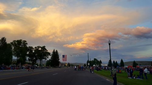 People on street against sky during sunset