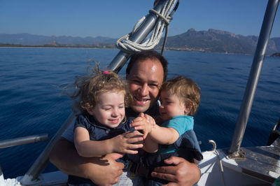 Portrait of father with children enjoying in boat on sea in sunny day