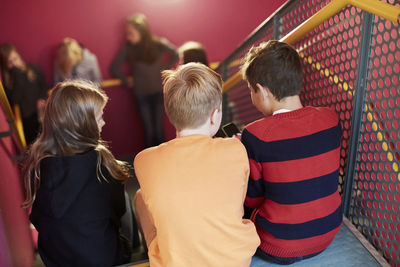 Rear view of junior high students sitting on staircase
