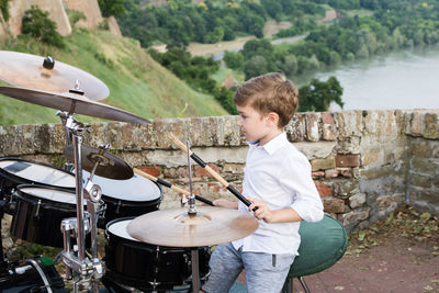 Boy playing drum kit outdoors