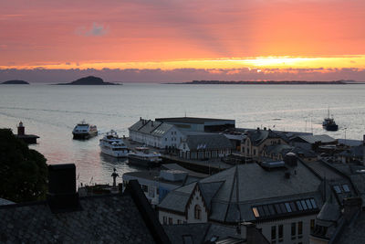 Boats moored at harbor during sunset