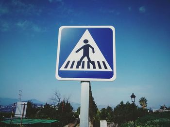 Low angle view of arrow sign against blue sky