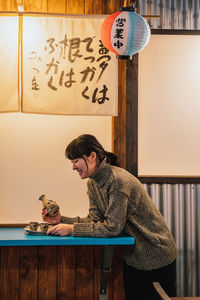 Young woman looking away while sitting on table