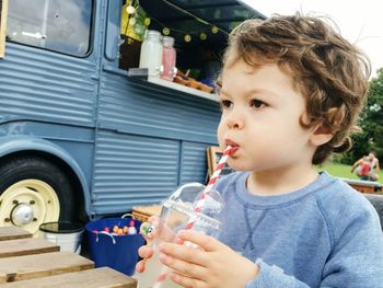 Close-up of cute boy drinking lemonade while looking away outdoors