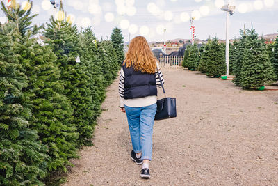 Rear view of woman standing against plants