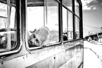 Senior man sleeping at window in bus