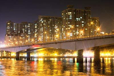 Illuminated bridge over river against sky at night