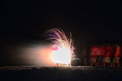 Illuminated firework on beach at night