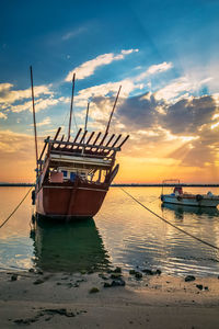 Sailboat moored on sea against sky during sunset