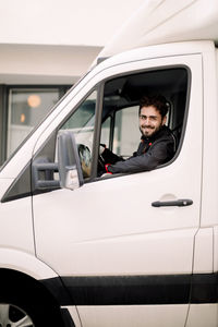 Portrait of smiling young delivery man driving truck