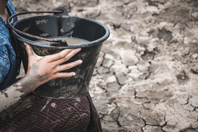 Midsection of girl filling water on drought land