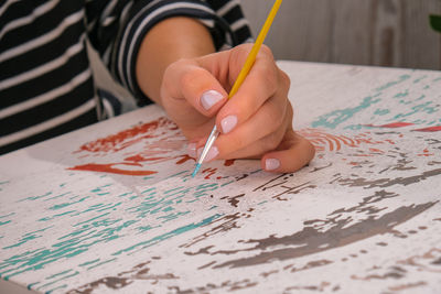 Painting on canvas by numbers and numbered jars of paint. woman draws with a brush painting 