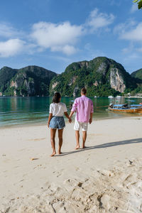 Rear view of women on beach against sky