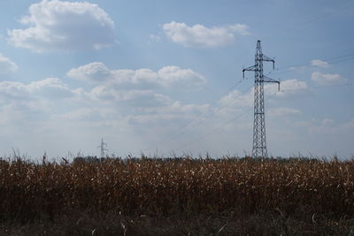 Low angle view of electricity pylon on field against sky