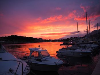 Boats moored at harbor during sunset