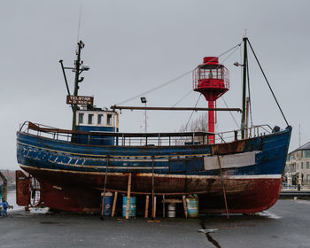 Abandoned ship moored on beach against clear sky