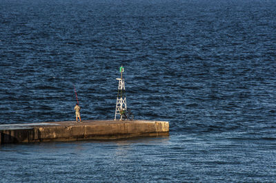 Man fishing while standing by lighthouse