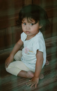 Portrait of cute girl sitting on hardwood floor