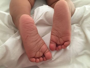 Low section of baby feet on bed