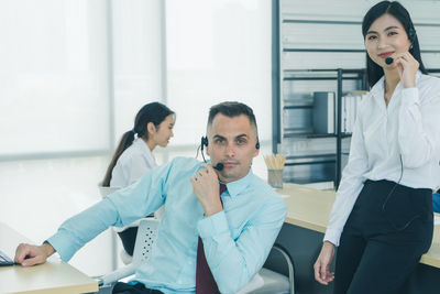 Portrait of smiling woman with colleagues at office