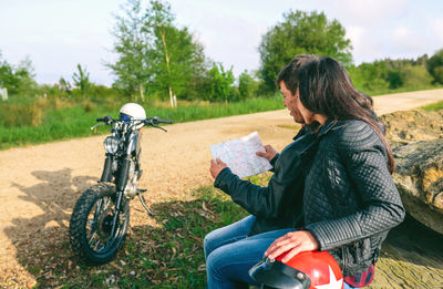 Young couple sitting looking at a map during a motorcycle trip