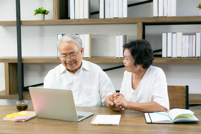 Man and woman using laptop while sitting at table