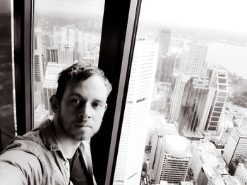 Portrait of young man looking through window